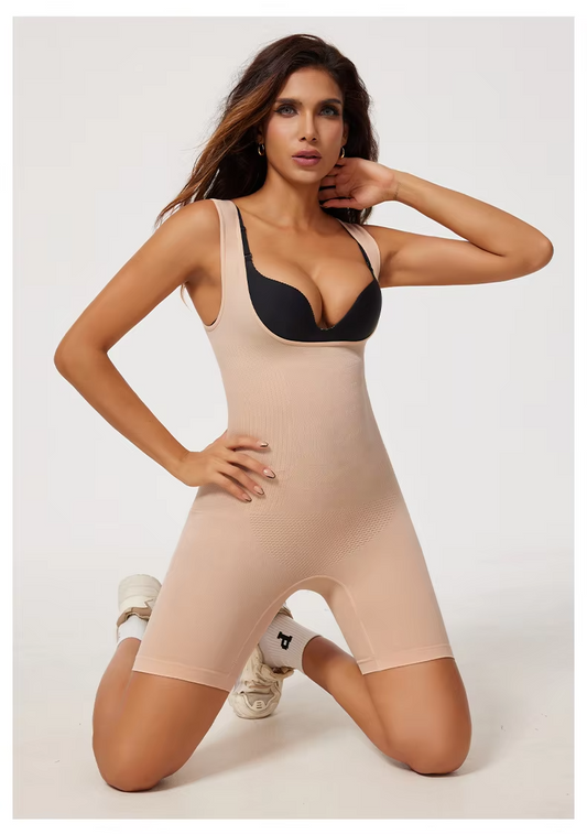 Woman wearing a beige bodysuit with a black bralette on a white background