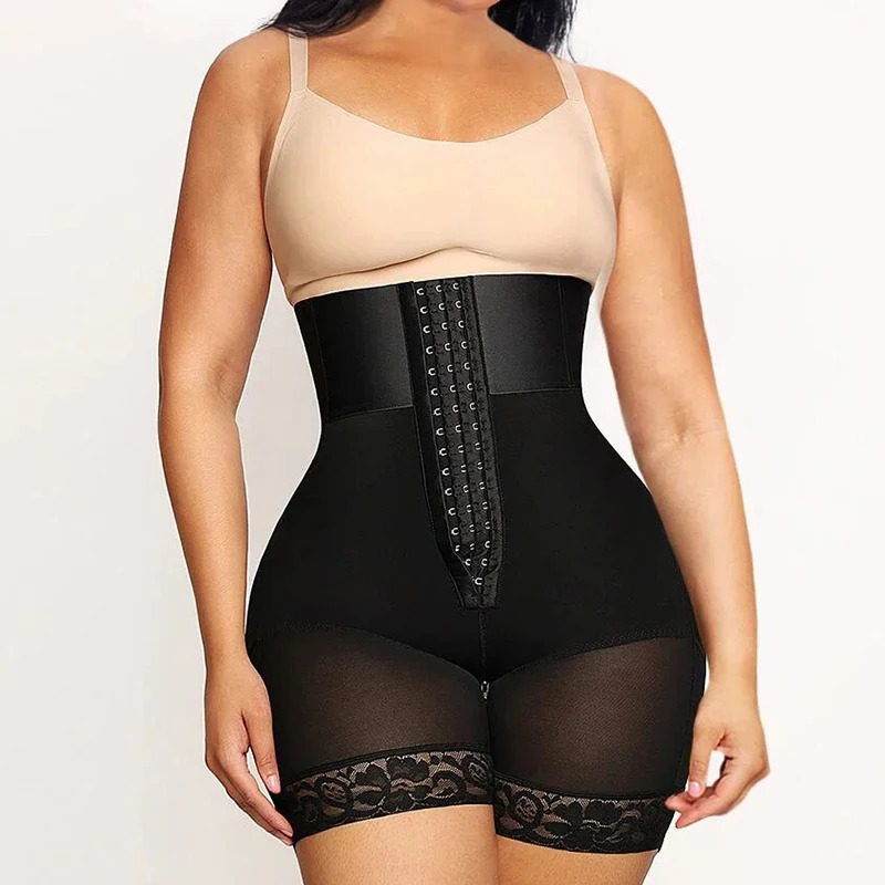Woman wearing a black waist trainer with lace details on a plain background